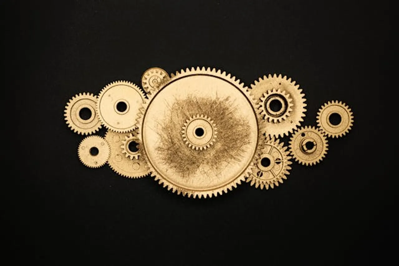 Free Artistic arrangement of gold gears on a black background symbolizing industry. Stock Photo